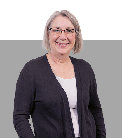Frau mit kurzen Haaren und Brille lacht in die Kamera.